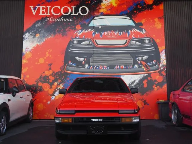 Toyota Sprinter Trueno AE86 panda blanc et noir de trois quarts avant, phares escamotables relevés