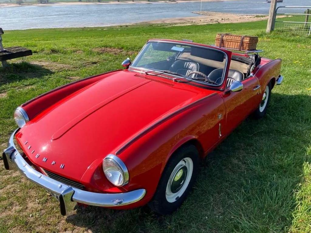 Triumph Spitfire Mk3 Signal Red de trois quarts avant, capot basculant fermé, petit roadster anglais capote baissée